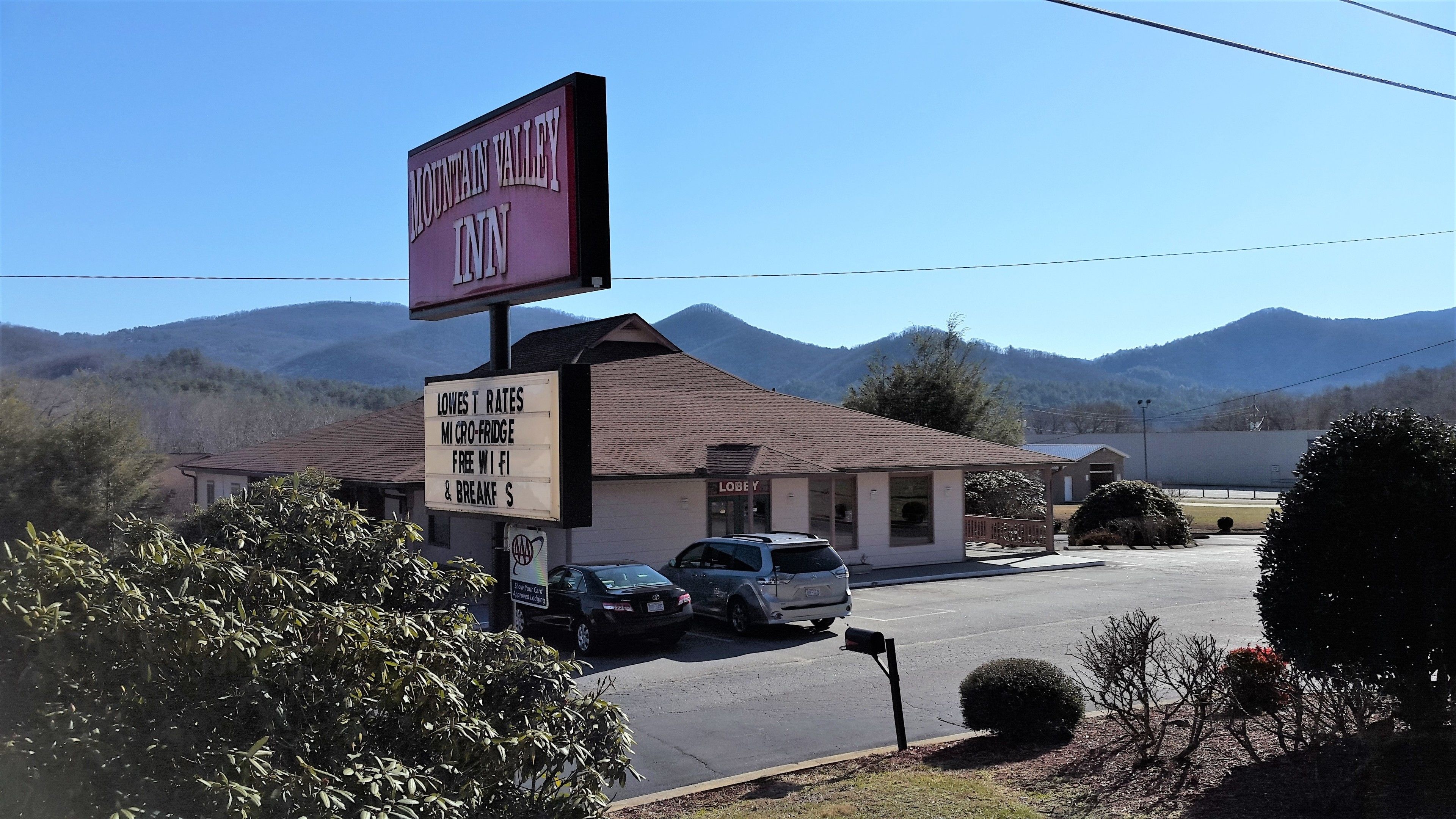 A Mountain Valley Inn with a sign advertising the lowest rates, a mini-fridge, free Wi-Fi, and breakfast.
