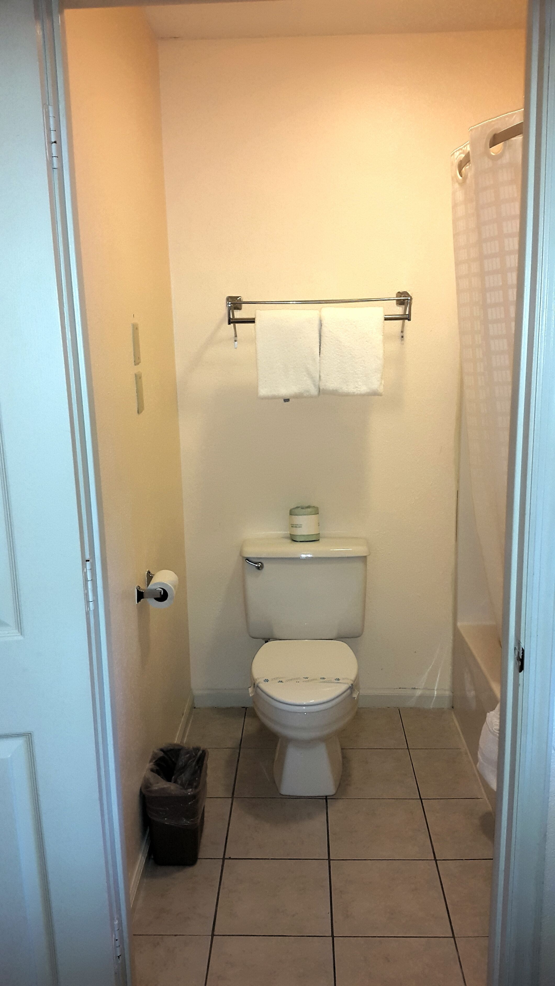 A small, clean bathroom with a toilet, a trash can, and a towel rack.