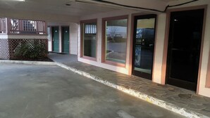 Un edificio con un espacio exterior cubierto, un acceso empedrado en piedra y una puerta negra.