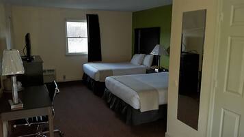Habitación de hotel con dos camas, un escritorio con lámpara, una silla y una ventana con cortinas.