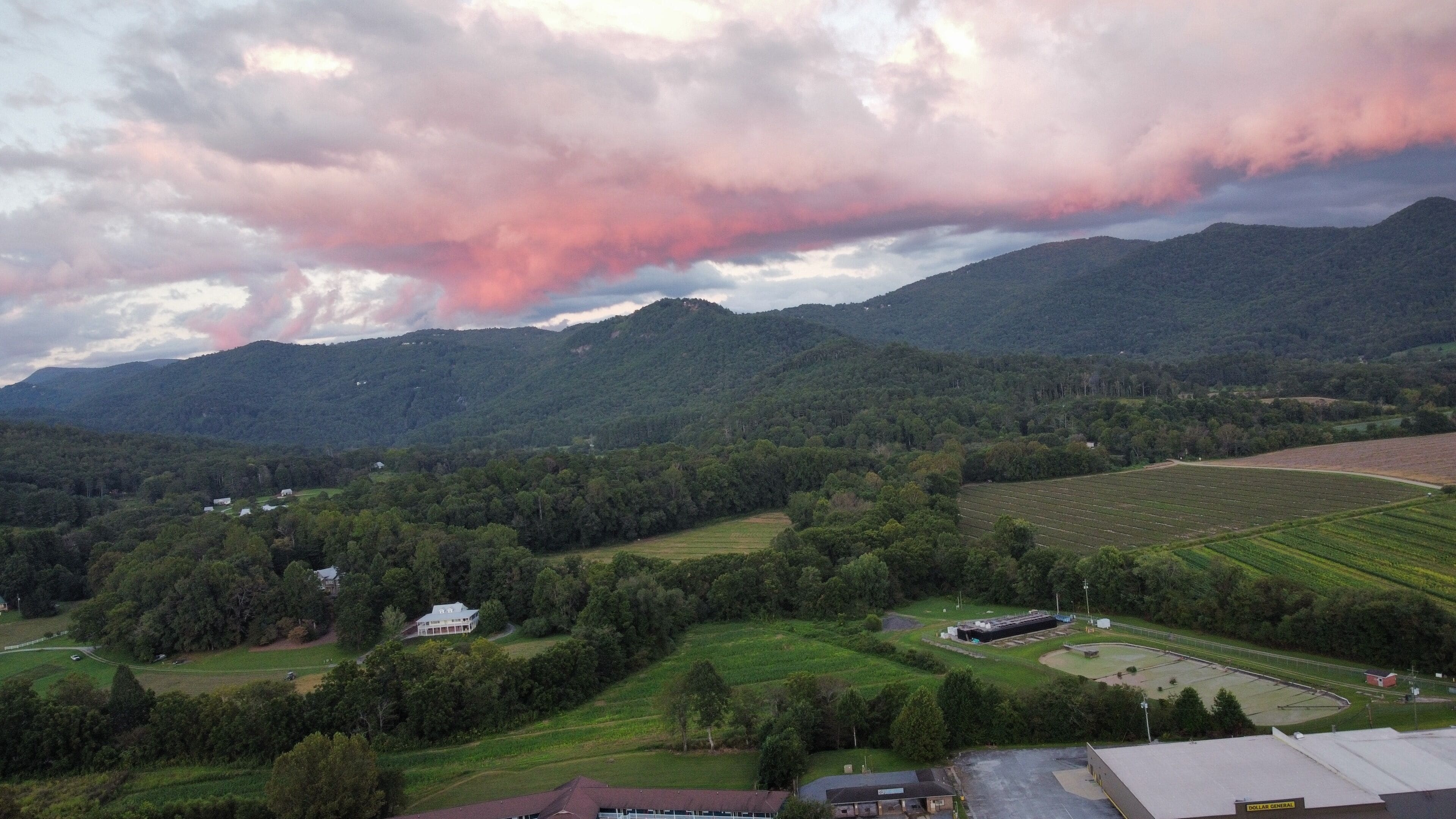 Un paysage rural avec des montagnes, des champs et quelques bâtiments.