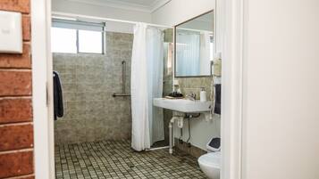 Une salle de bain avec une douche, un lavabo et des toilettes.