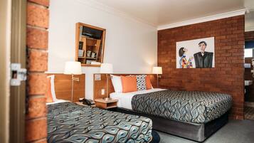 Ein Hotelzimmer mit zwei Betten, einer Ziegelwand, einem Gemälde und einem Holzregal mit Gegenständen.