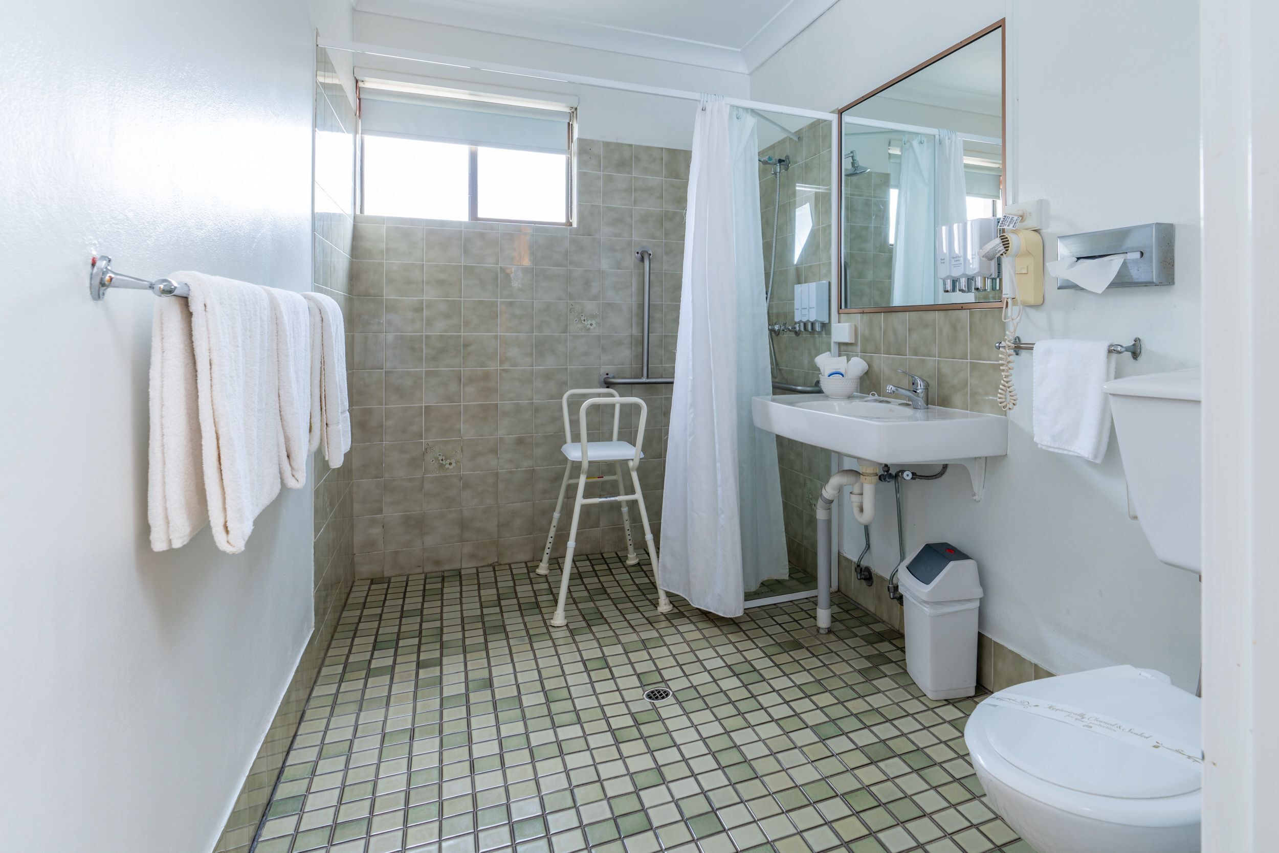 Un baño con ducha, inodoro, lavamanos y espejo.