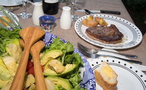 A table set with a salad, steak, bread, and a cup of coffee.