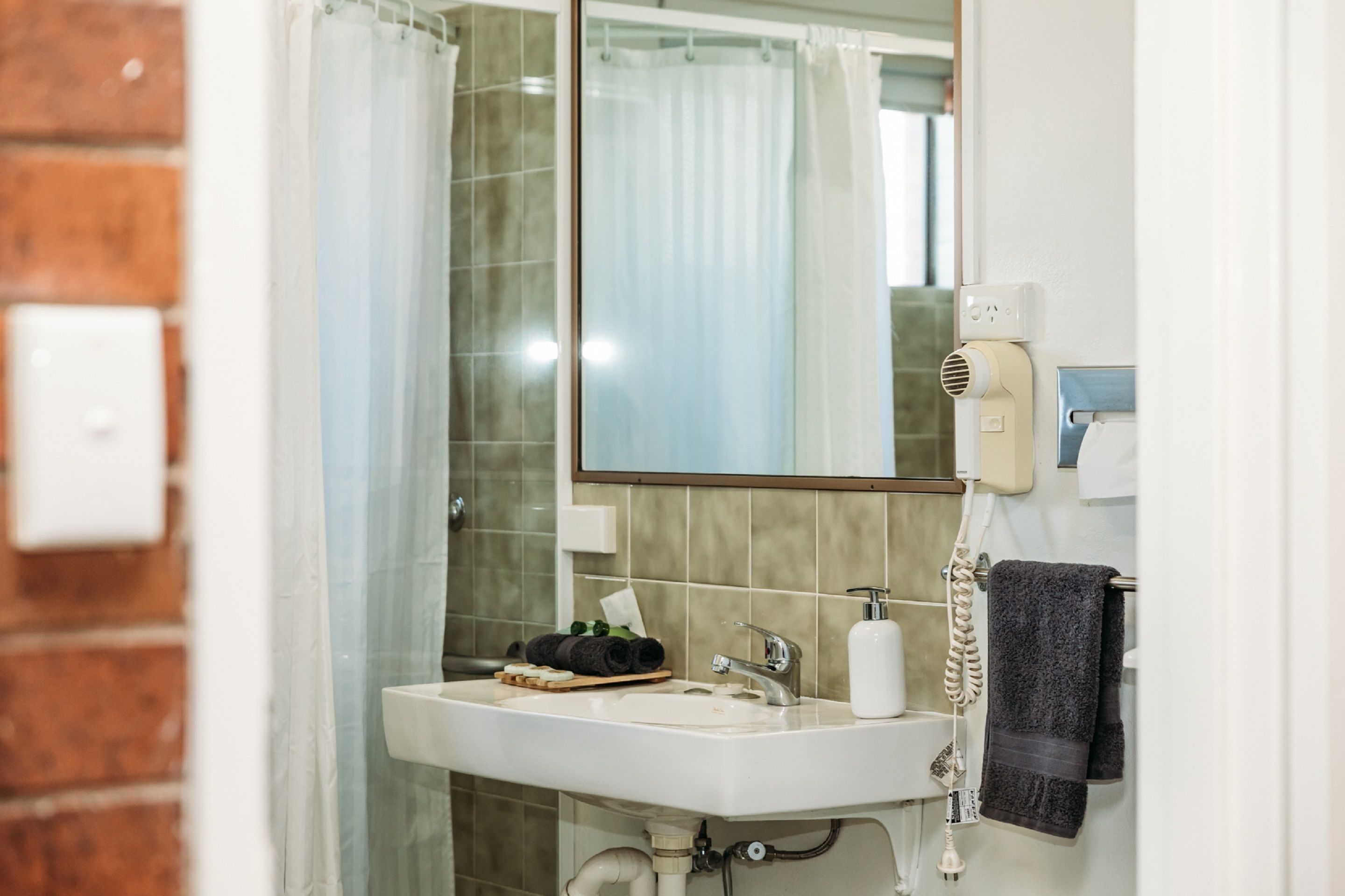 A bathroom with a white sink, a mirror, a hairdryer, and a towel rack.