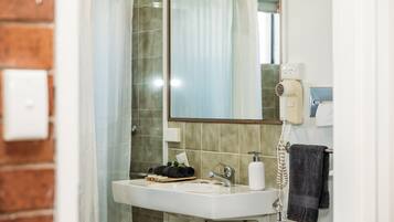 A bathroom with a white sink, a mirror, a hairdryer, and a towel rack.
