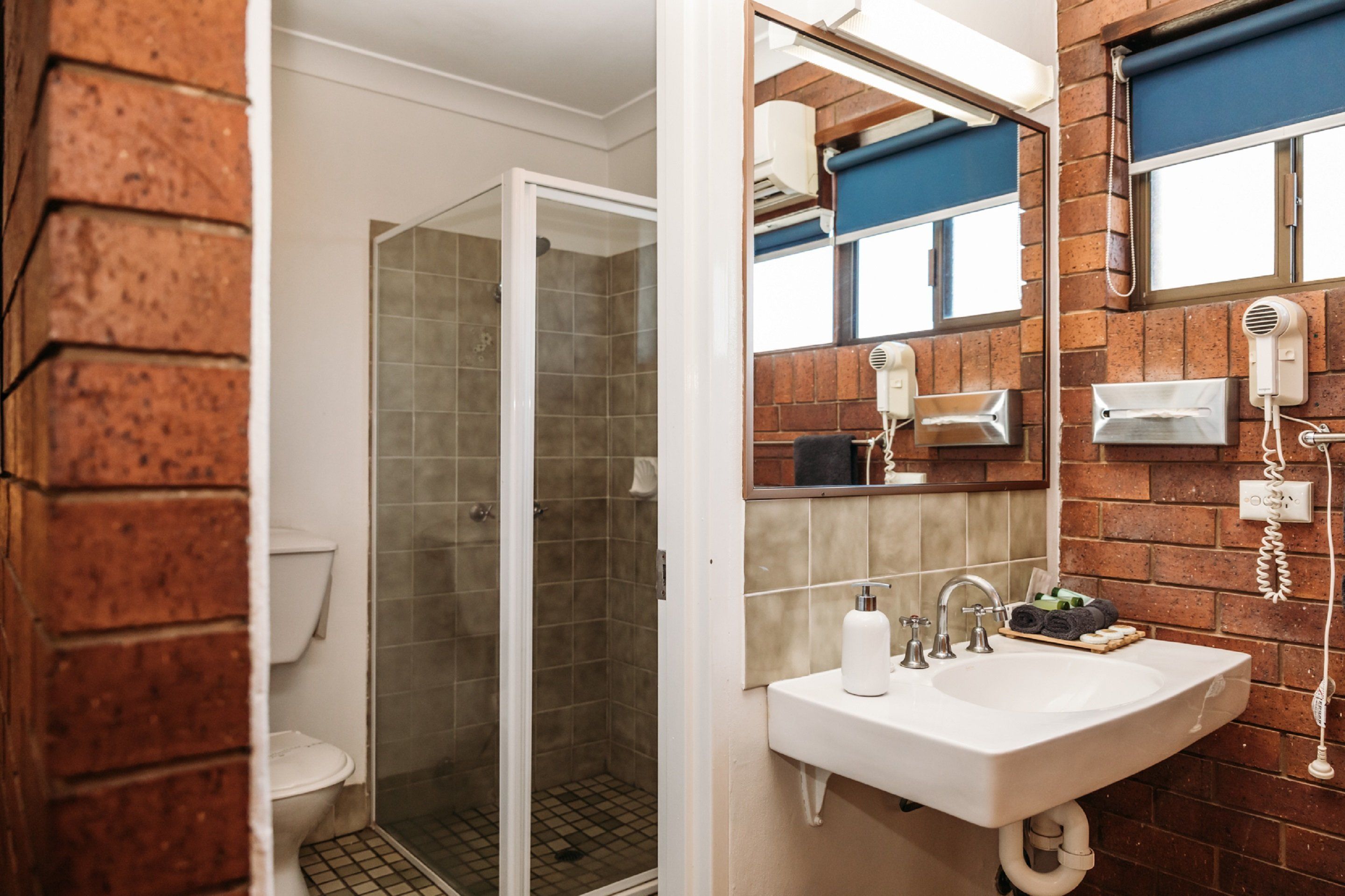 Un baño con ducha de vidrio, un lavabo blanco y un espejo con toallero.