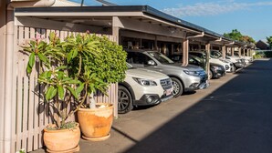 Una fila de coches aparcados en un estacionamiento cubierto, con un edificio al fondo.