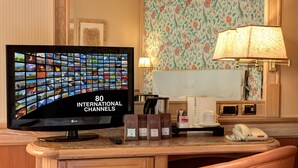 Hotelkamer met een flatscreen televisie waarop 80 internationale zenders, een bureau met telefoon, een koffiekop en een lamp.