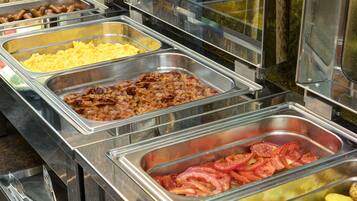 Un bufé con diversas opciones de comida, incluyendo carnes, huevos y vegetales.