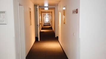 Pasillo de hotel con puertas a ambos lados, suelo alfombrado y un cartel que indica el número 123.