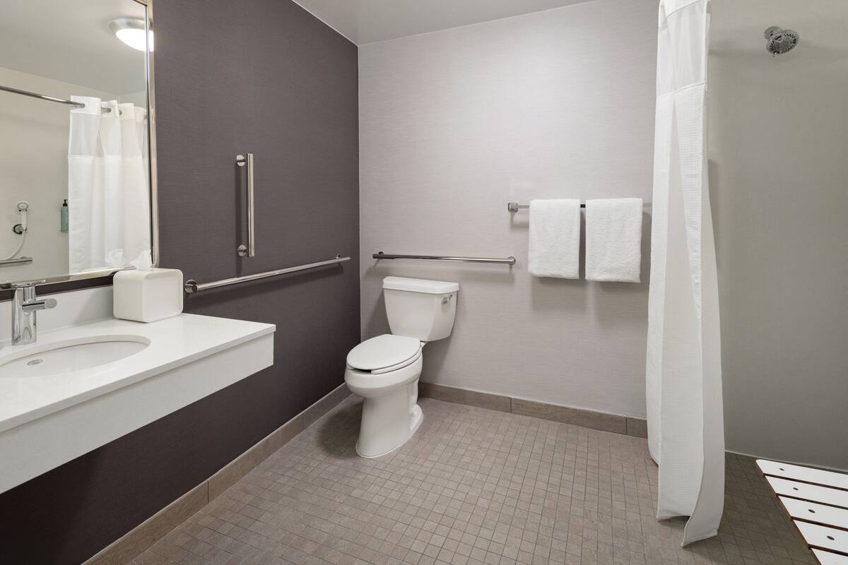 A modern bathroom with a white sink, toilet, and shower curtain.
