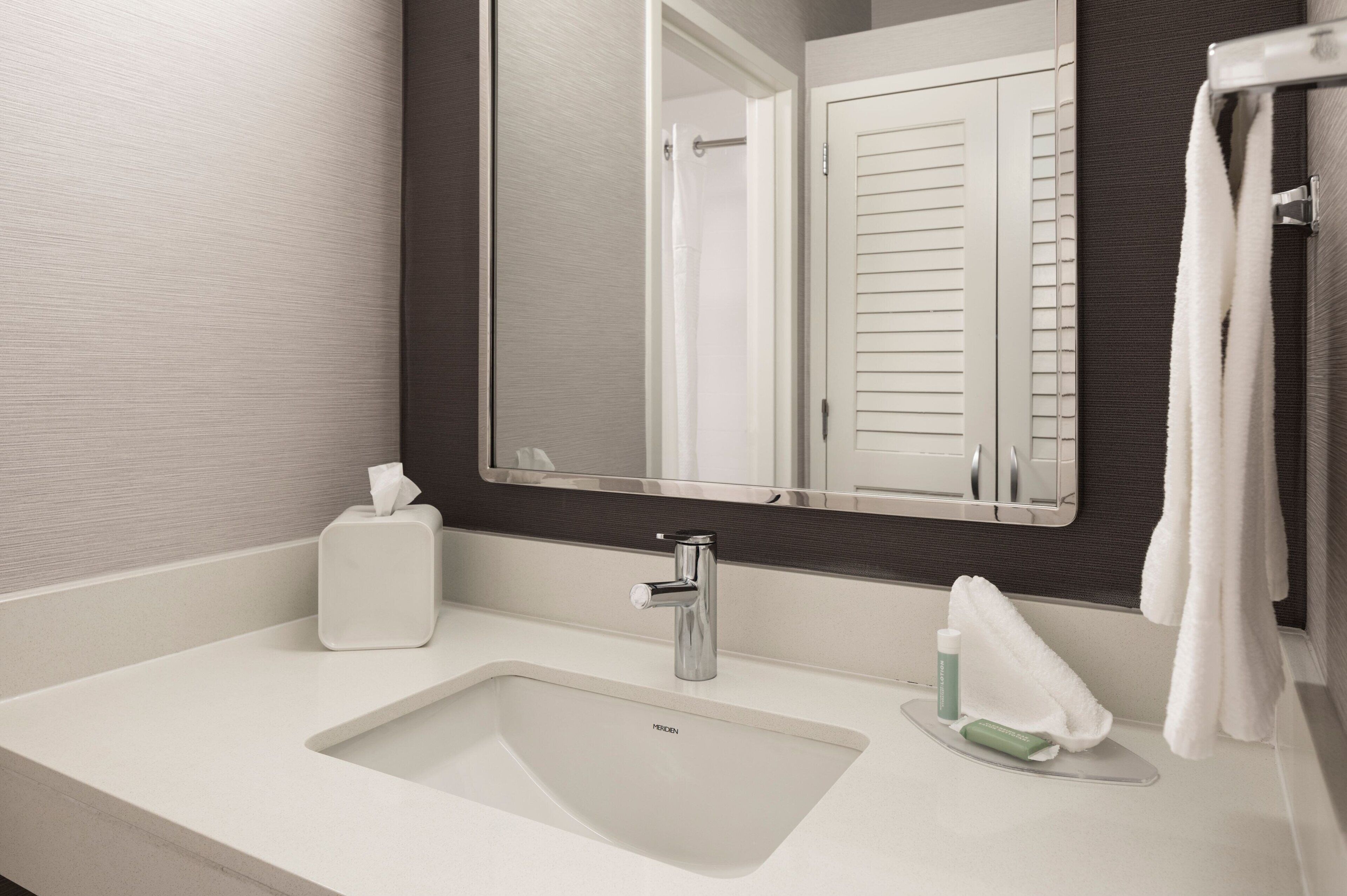 A modern bathroom with a white sink, a mirror, and a towel rack.