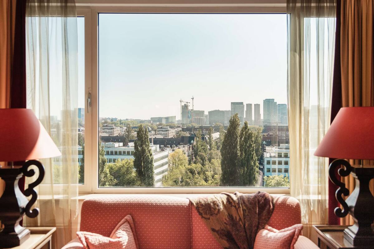 Una habitación con un amplio ventanal que ofrece vistas a la ciudad, un sofá y dos lámparas.