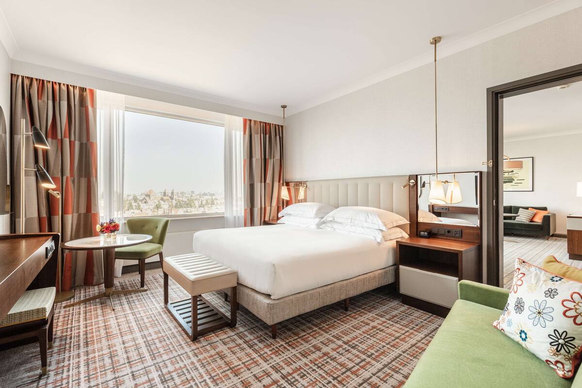 Una habitación de hotel con una cama grande, un escritorio, una silla, una mesita y un sofá.