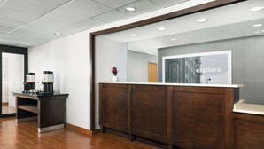 A reception area with a wooden reception desk, a coffee machine, and a vase with flowers. - Hampton Inn Laredo (Laredo)