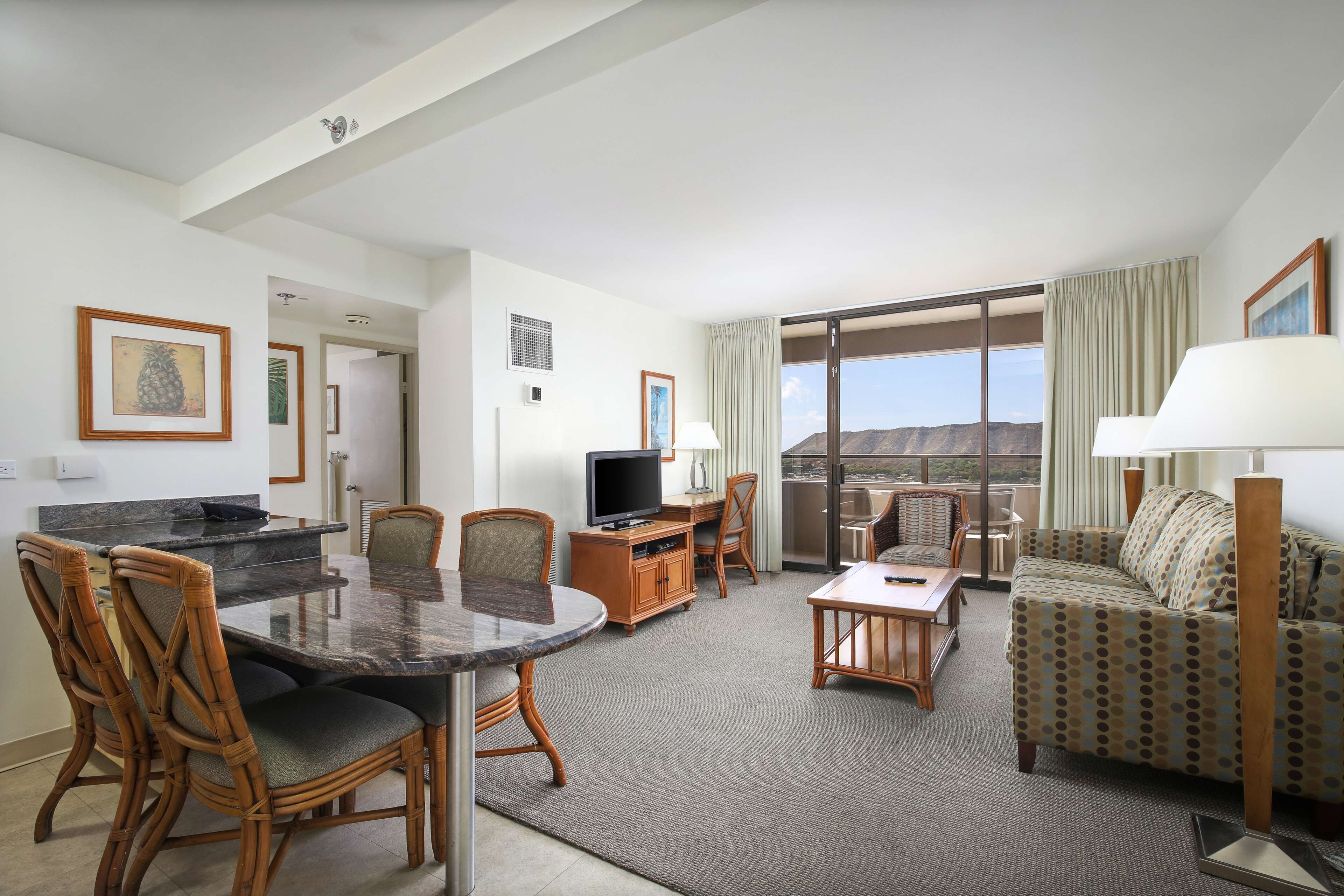 Habitación de hotel con comedor, sofá, televisor y vistas a las montañas.