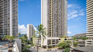 A high-rise hotel with multiple floors, balconies, and a view of the surrounding cityscape. - Aston Waikiki Sunset (Honolulu)
