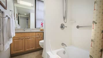 Une salle de bain avec une baignoire, des toilettes et des meubles en bois.