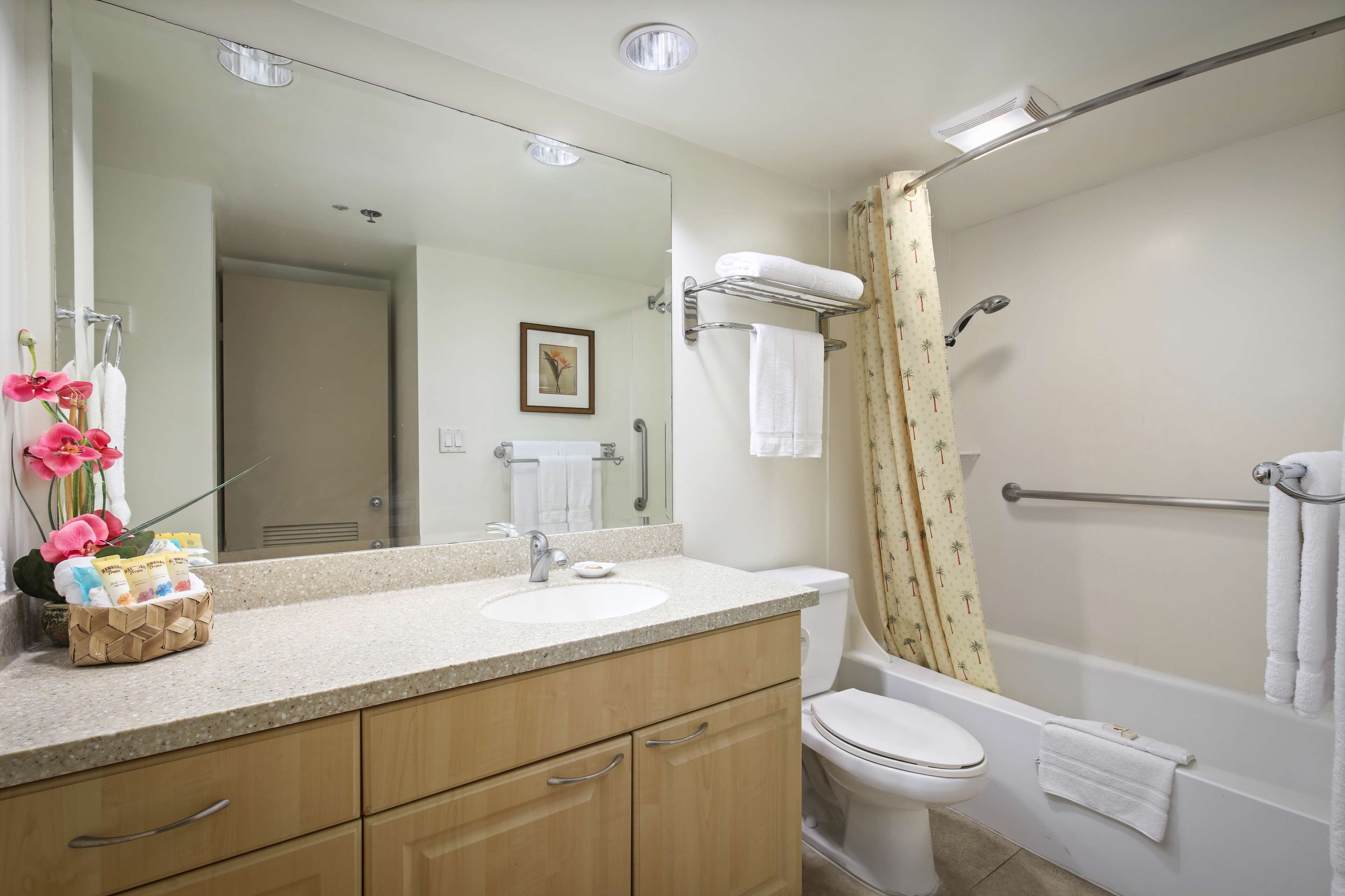 A bathroom with a sink, mirror, toilet, and shower.