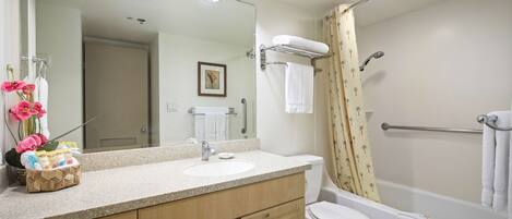 A bathroom with a sink, mirror, toilet, and shower.