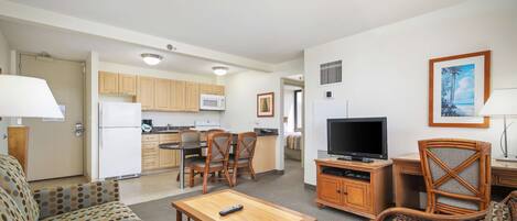 A compact living space with a kitchenette, a sofa, a dining table, and a TV.