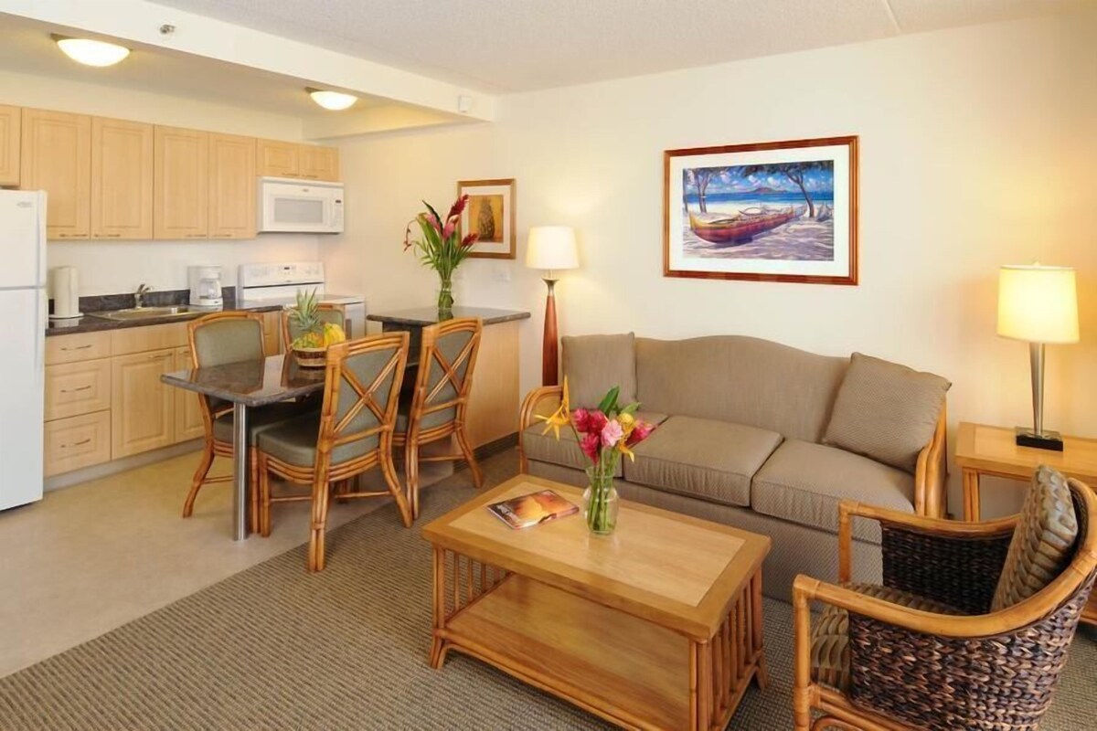 Quarto de hotel compacto com cozinha compacta, um sofá, uma mesa de jantar com cadeiras e uma mesa de centro.