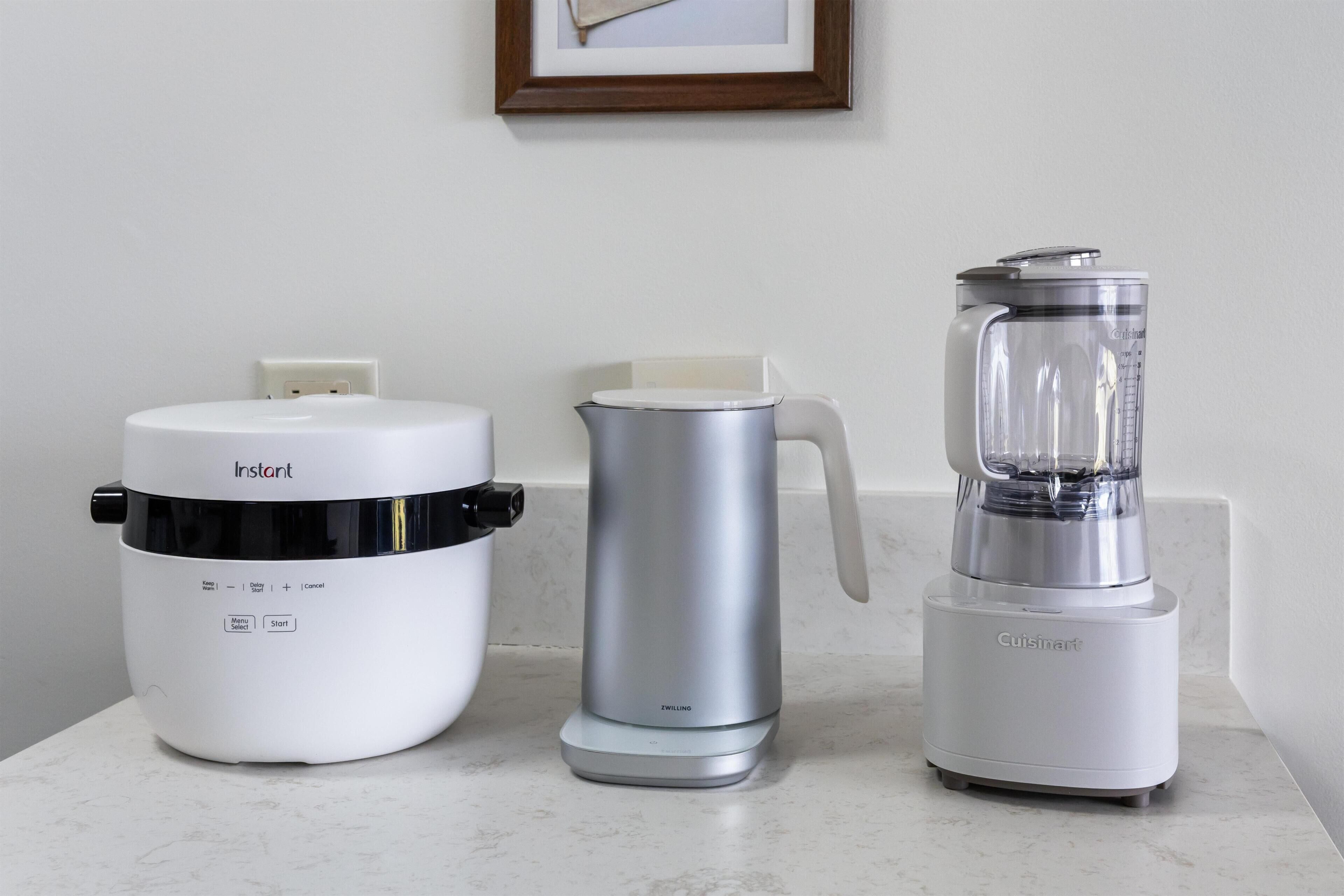 A kitchen countertop with an Instant coffee maker, a silver electric kettle, and a Cuisinart blender.