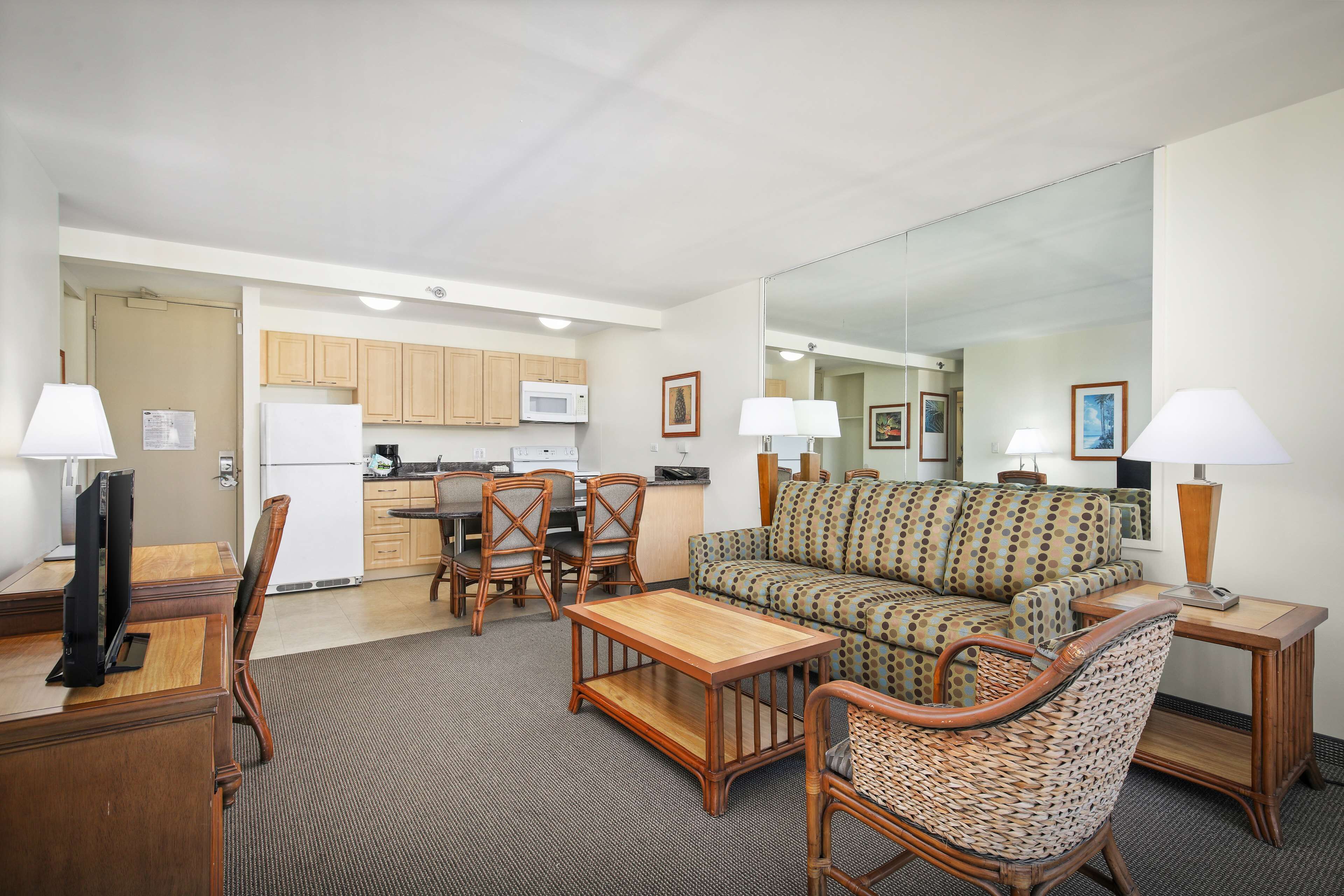 A compact living space with a sofa, chairs, a dining table, and a kitchen area.