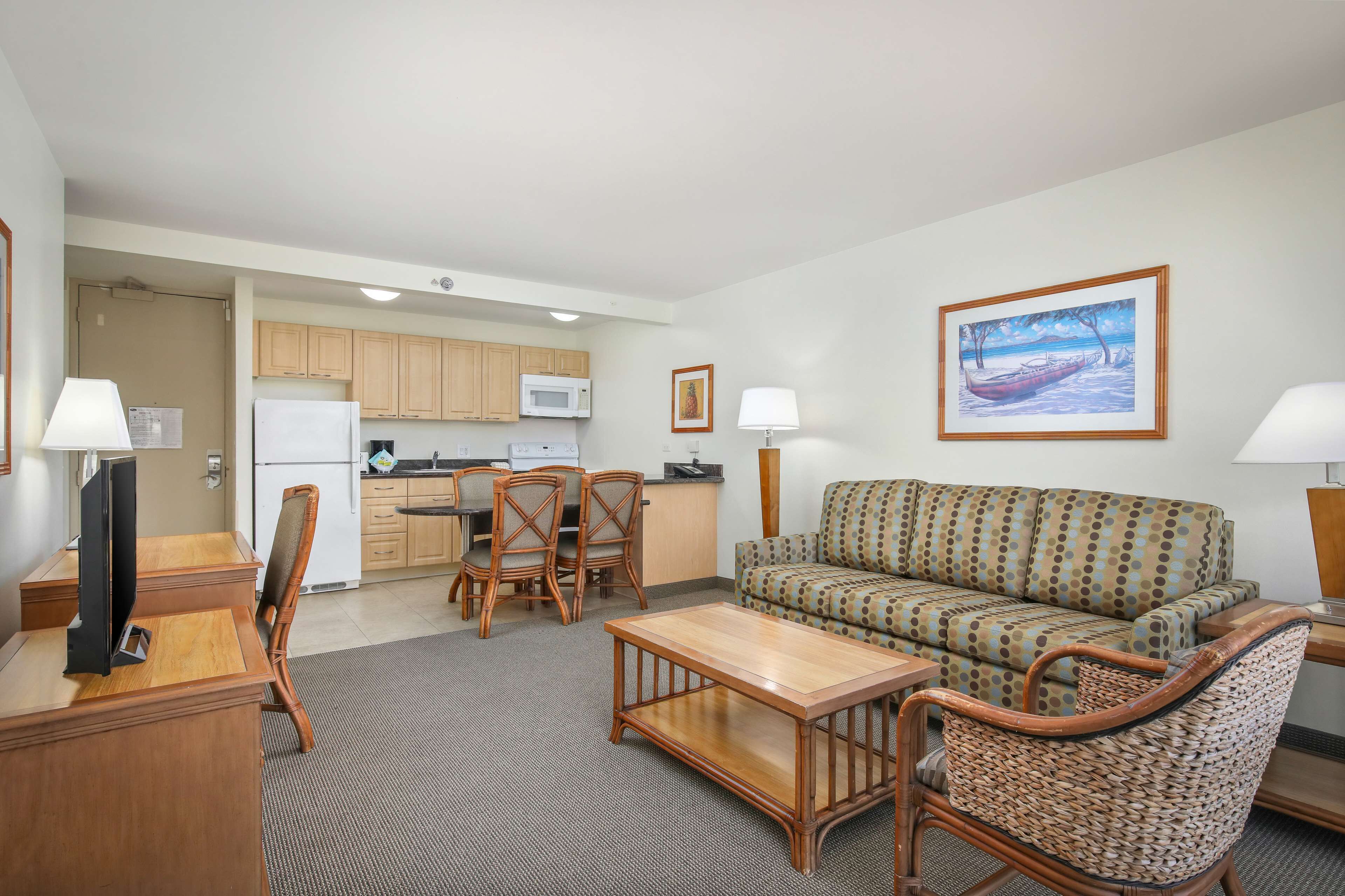 A compact living space with a kitchenette, a sofa, a dining table, and two chairs.