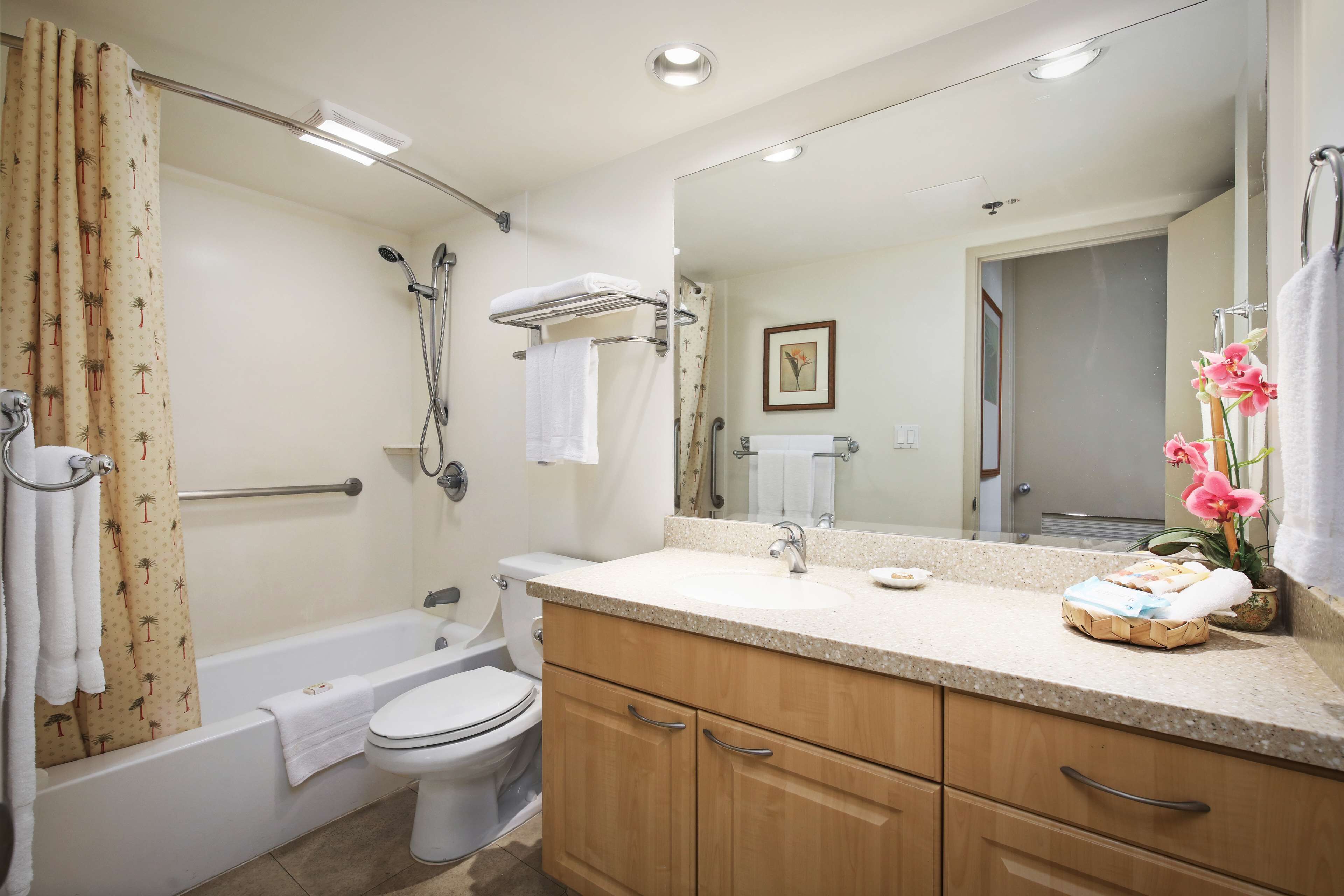 A bathroom with a bathtub, toilet, vanity with a mirror, and a shower area.