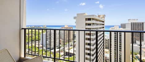 A balcony with wicker furniture, a view of a cityscape, and a clear sky.