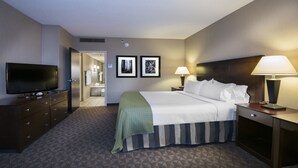 A hotel room with a bed, a TV, a lamp, and a picture of a forest on the wall. - Holiday Inn Springdale/Fayetteville Area by IHG (Springdale)