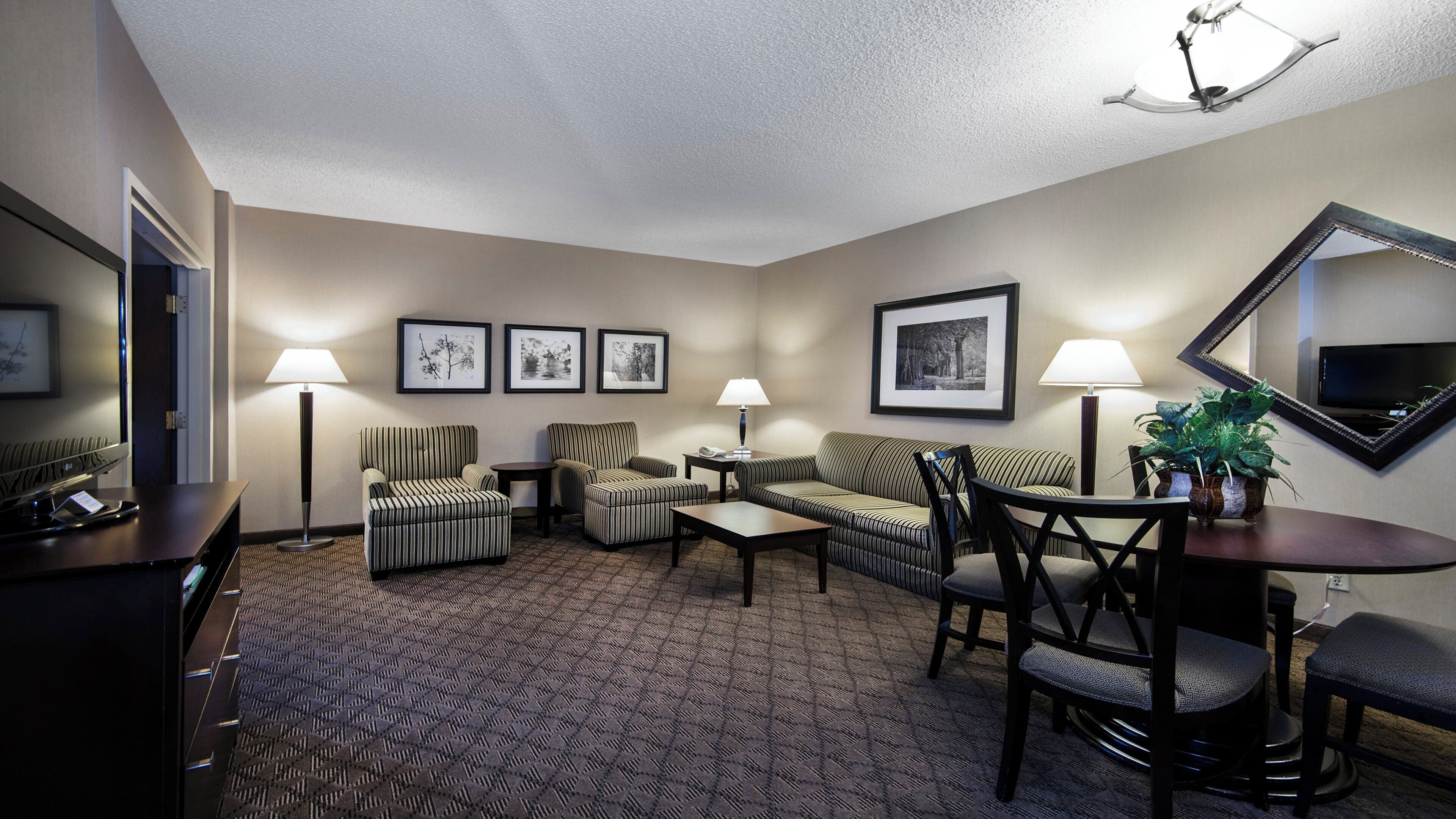 Quarto de hotel com área de estar, TV de tela plana e quadros na parede.