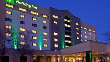 A Holiday Inn hotel with multiple floors, a well-lit entrance, and a parking area.
