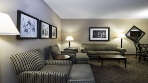 A hotel room with striped furniture, framed pictures on the wall, and a carpeted floor. - Holiday Inn Springdale/Fayetteville Area by IHG (Springdale)