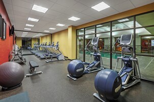 Un gimnasio con cintas de correr, elípticas y pelotas de ejercicio.