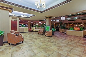 A hotel lobby with a reception desk, seating area, and a large plant. - Holiday Inn Springdale/Fayetteville Area by IHG (Springdale)