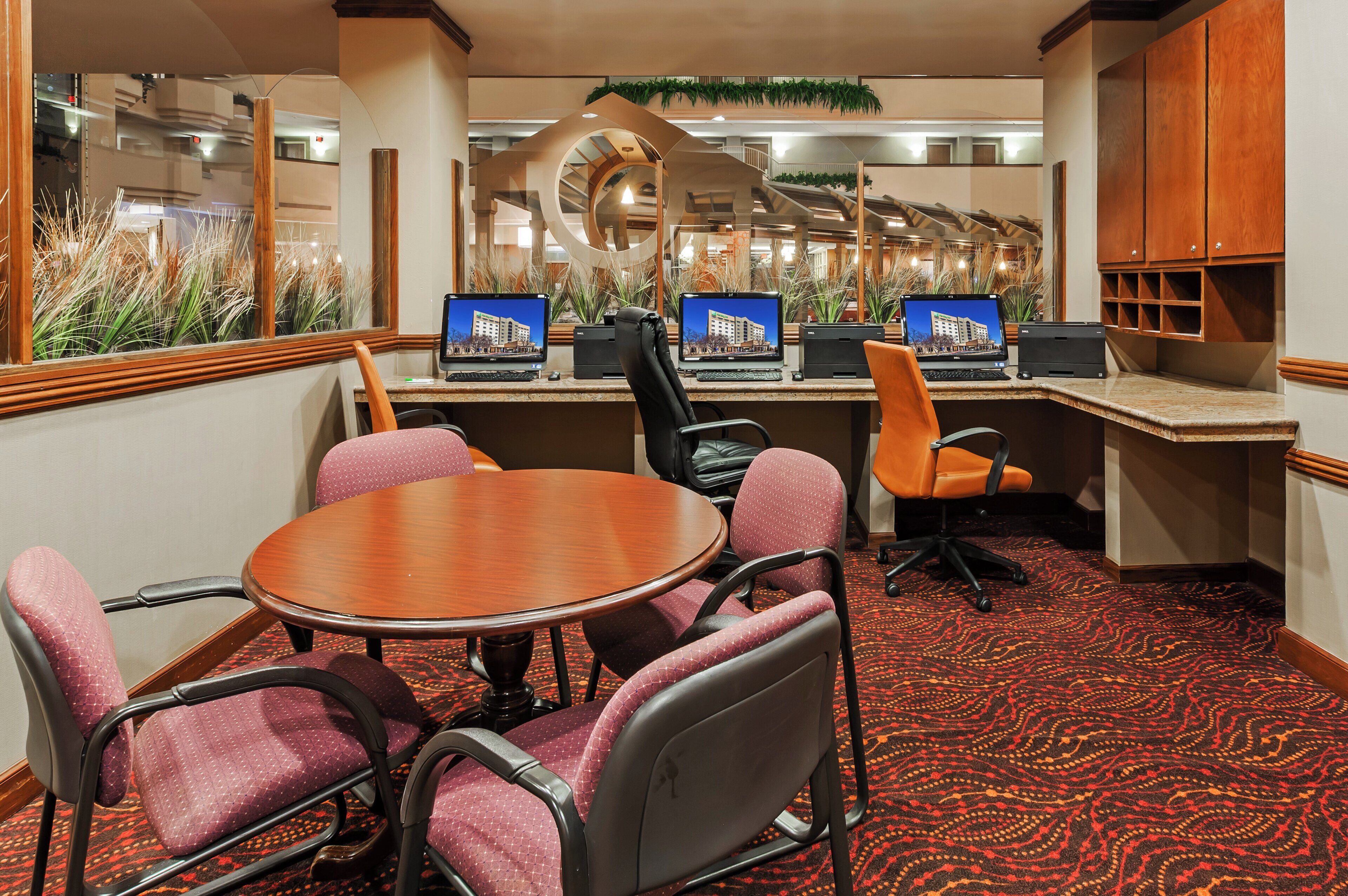 A conference room with a round table, four chairs, and three desktop computers.