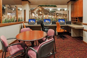 A conference room with a round table, four chairs, and three desktop computers.