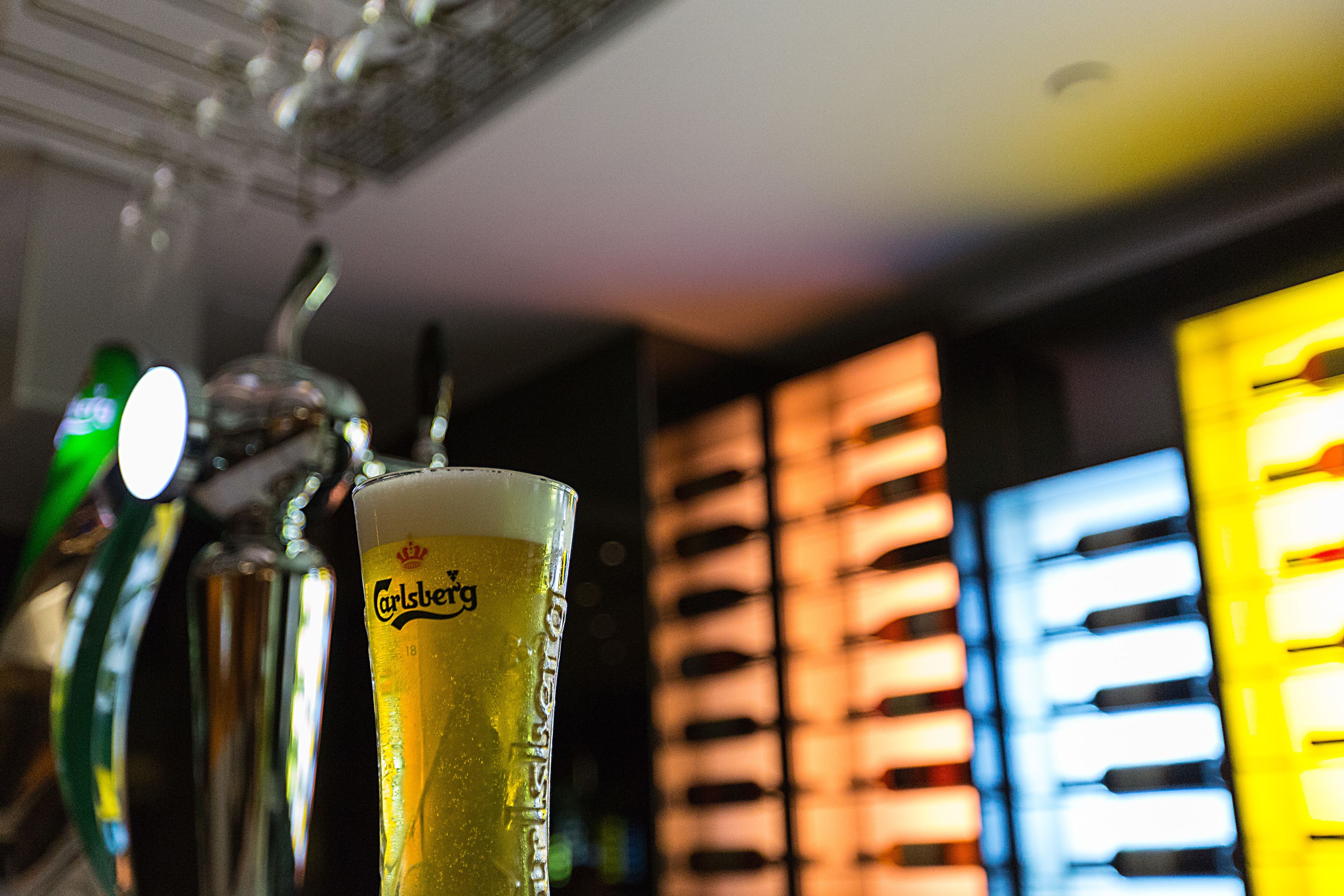Una cerveza con etiqueta, un grifo de cerveza y un fondo con pared estampada.