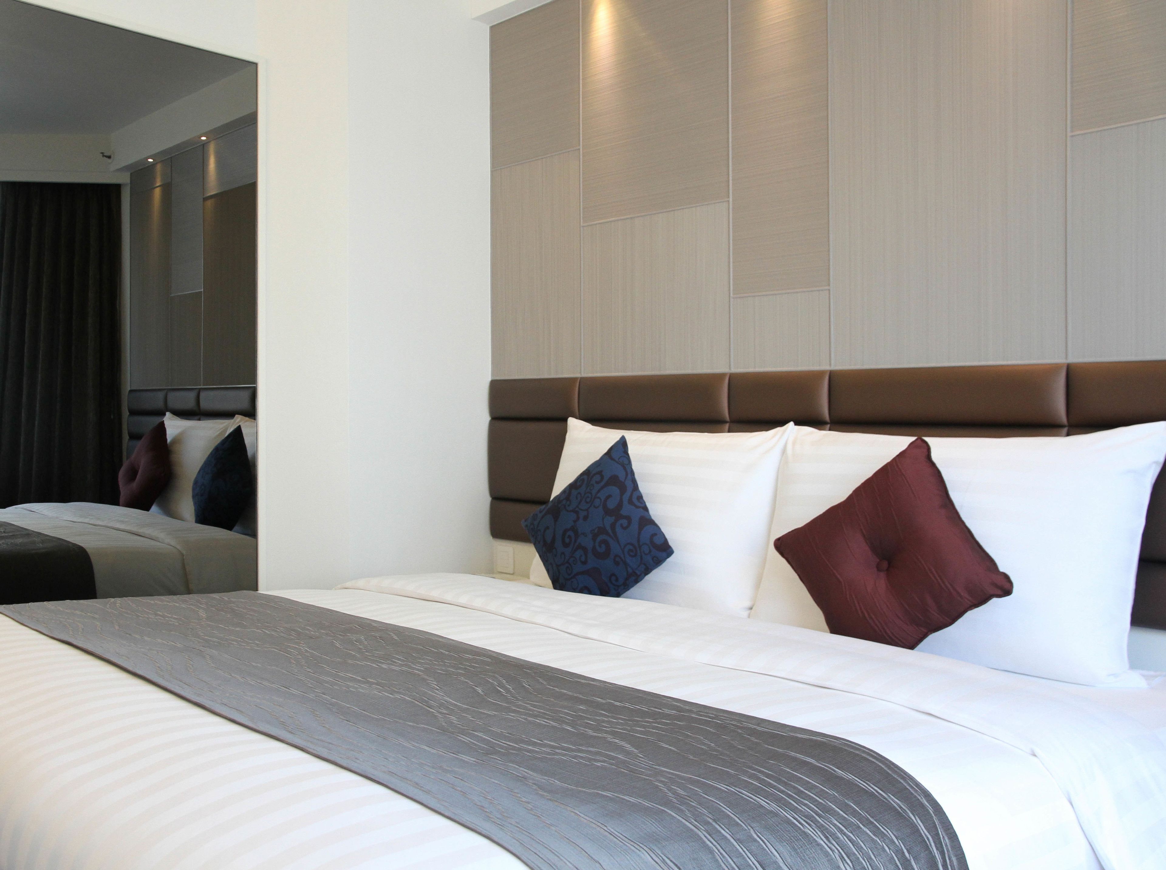 Una habitación de hotel con una cama grande, un cabecero y un espejo en la pared.
