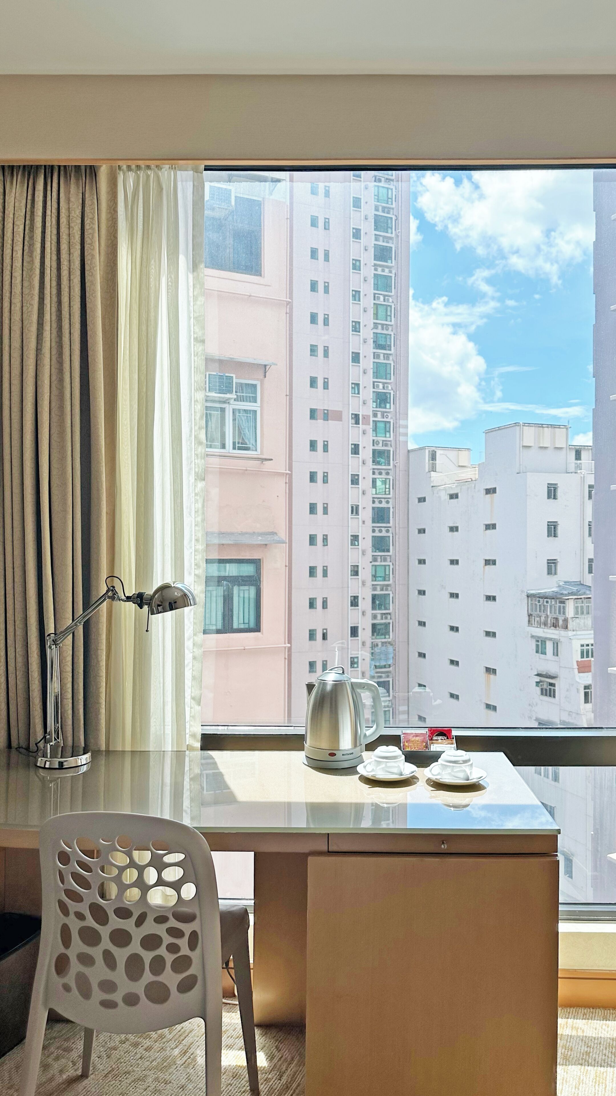 Une chambre d’hôtel avec une grande fenêtre, un bureau, une chaise et une machine à café.