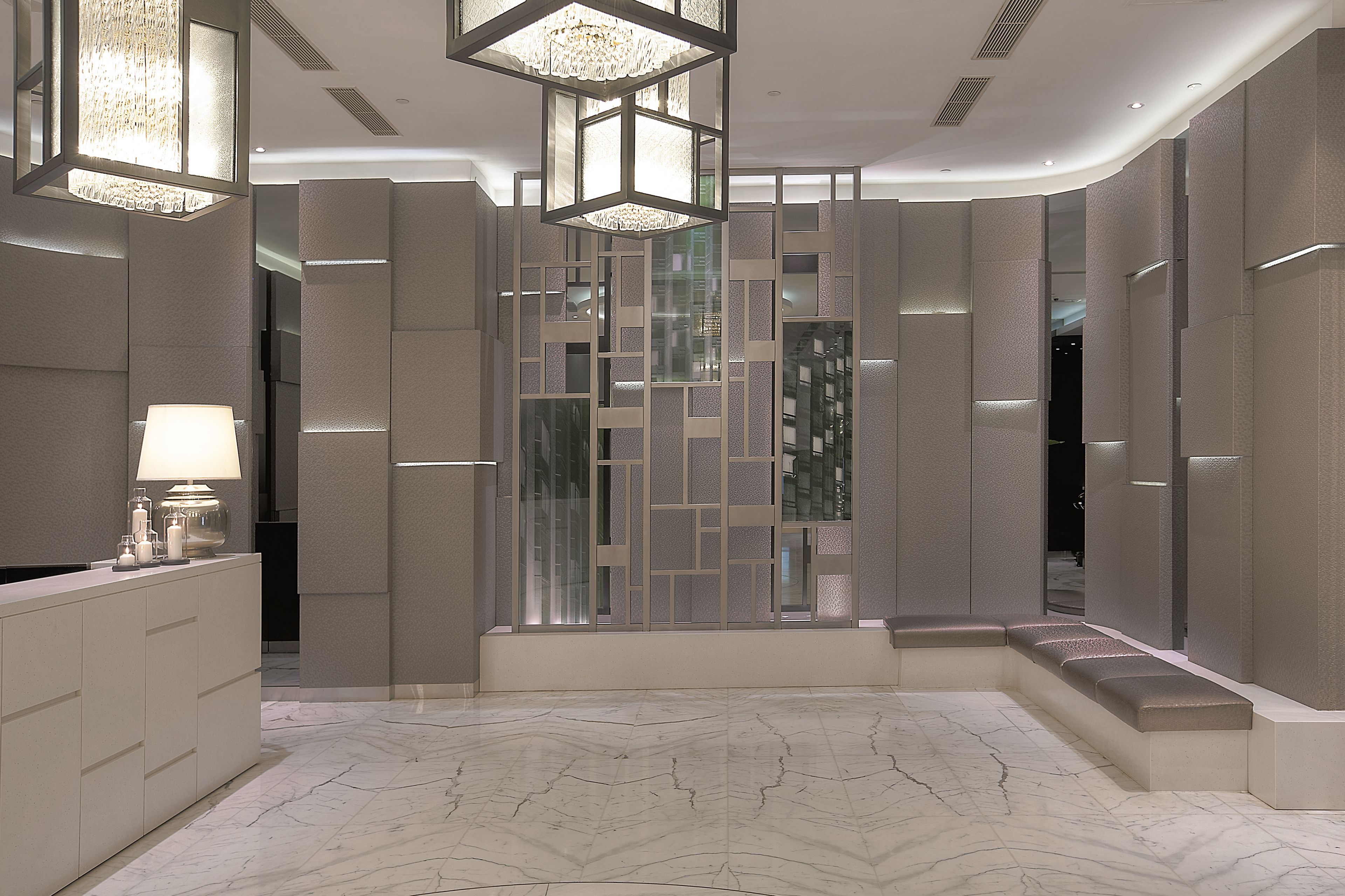 A modern interior with a marble floor, a reception desk, and a decorative partition with integrated lighting.