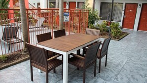 Un comedor con una mesa y sillas de madera, rodeado por un patio empedrado.
