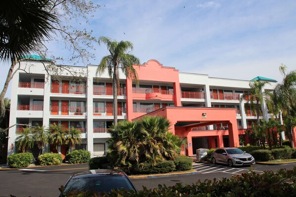 A multi-story hotel with balconies, palm trees, and a parking lot. - Boca Suites Deerfield Beach, SureStay Collection by BW (Deerfield Beach)