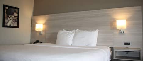 A hotel room with a large bed, two bedside tables with lamps, and a wall-mounted artwork.
