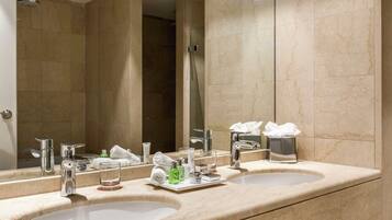 A hotel bathroom with two sinks, a large mirror, and a shower.