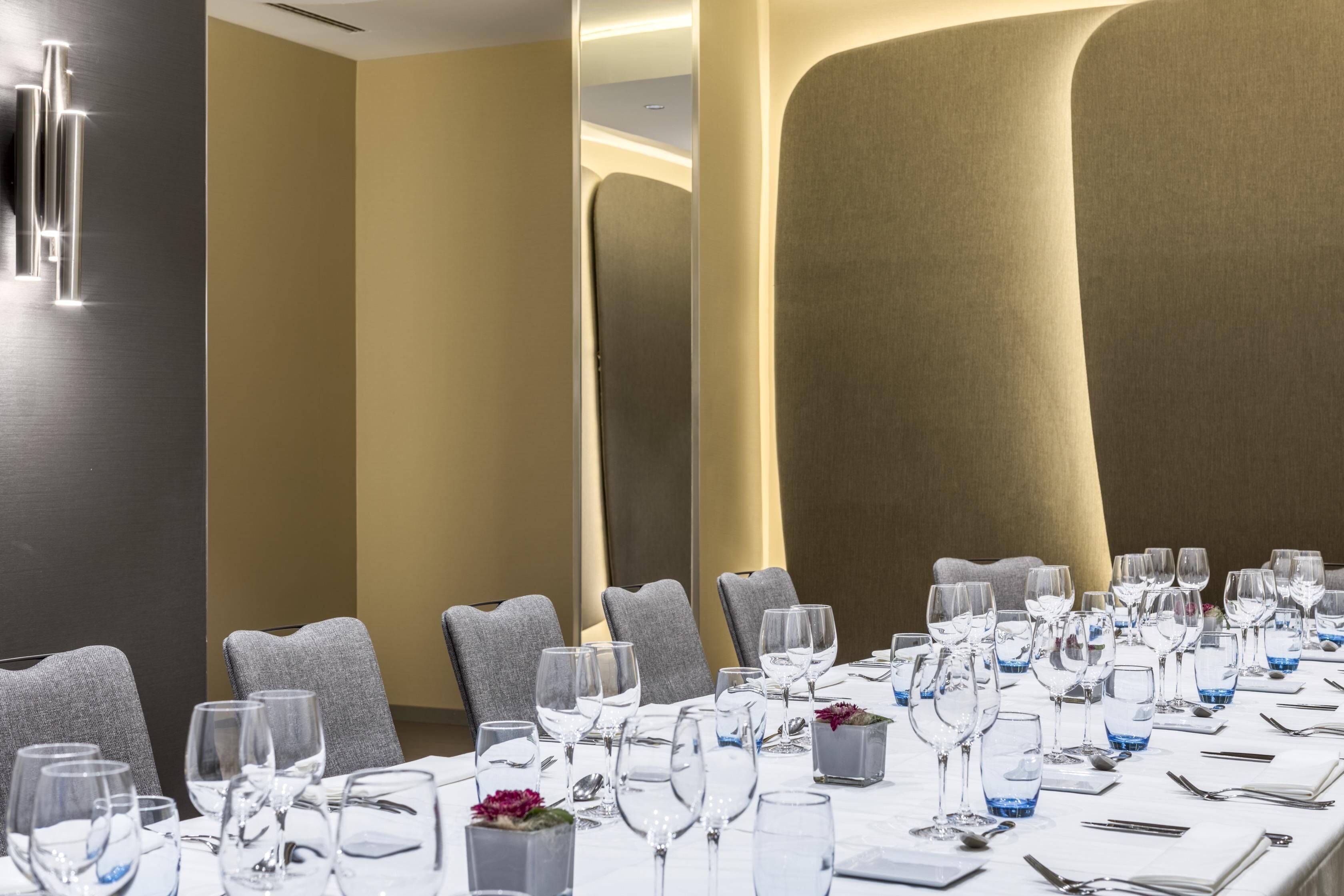 Une salle de conférence avec une longue table préparée pour une réunion, des chaises grises à revêtement en tissu et un décor mural moderne.